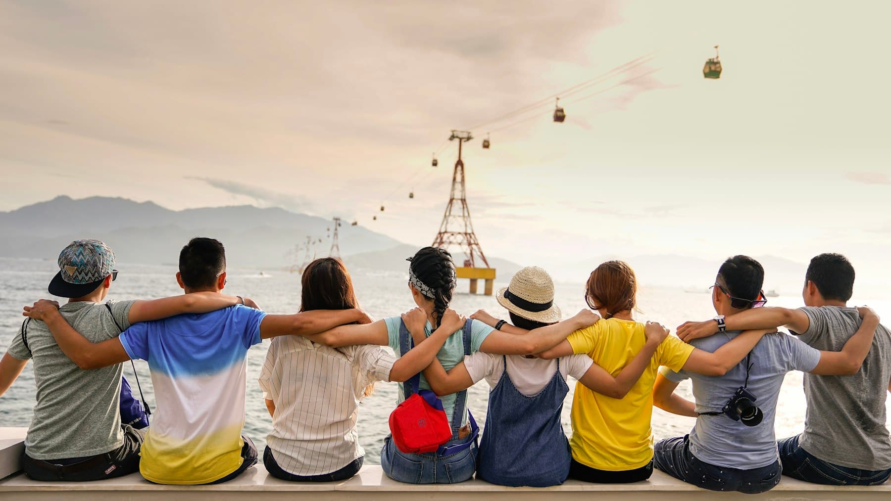 A row of friends sitting arm-in-arm looking out over the water